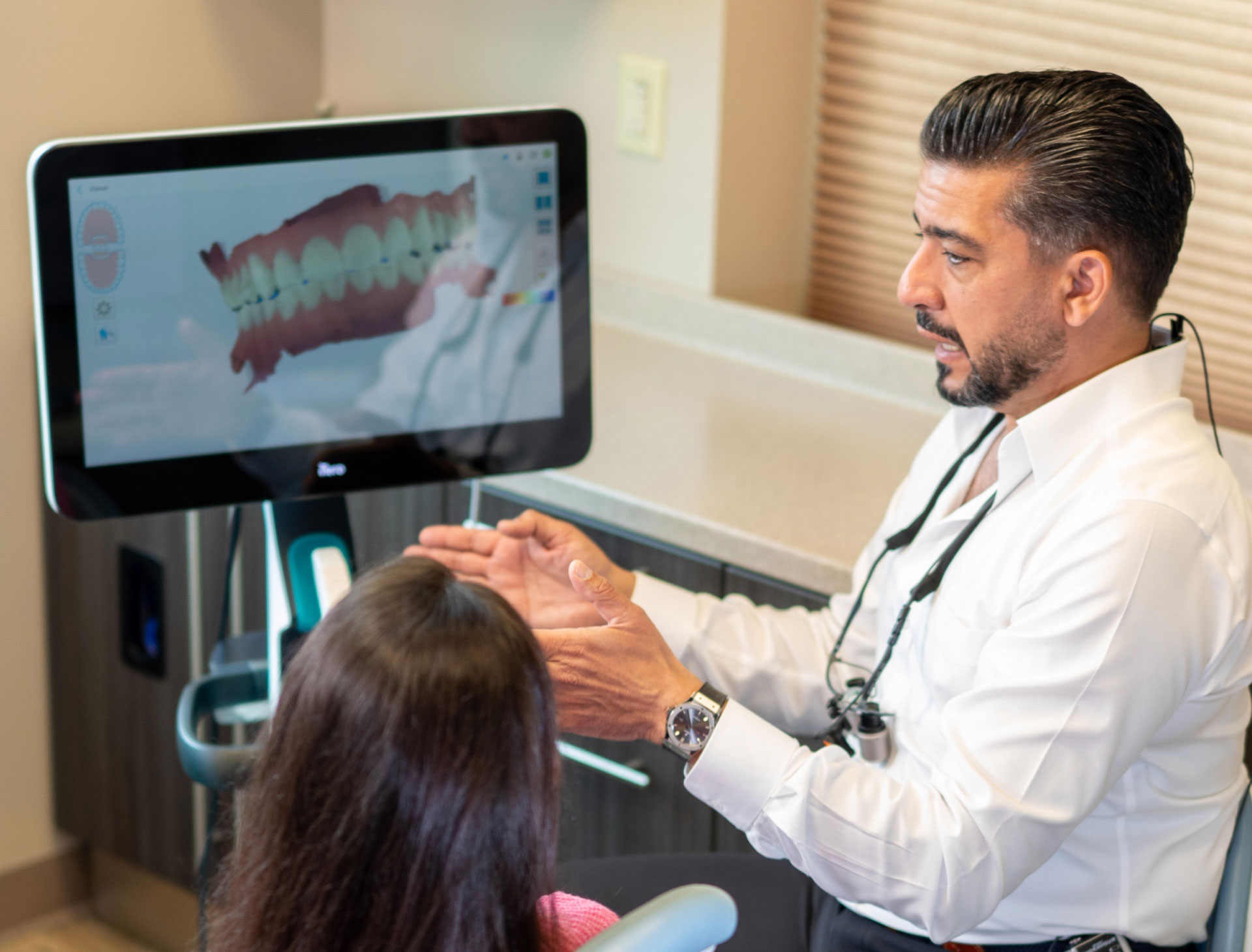 dentist talking to patient in exam room about dental scans on iTero monitor